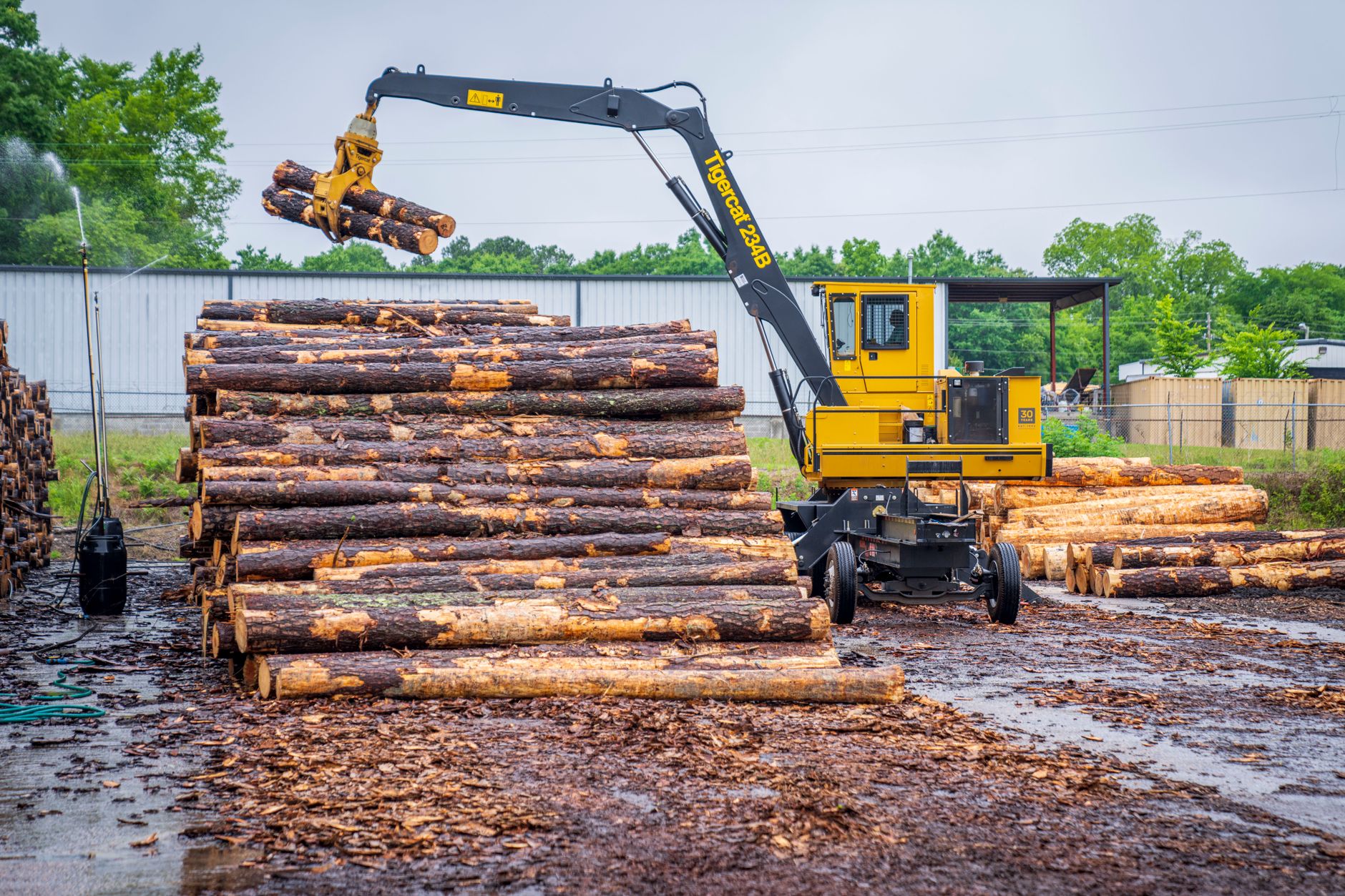 Un engin de manutention charge des grumes sur un parc à bois