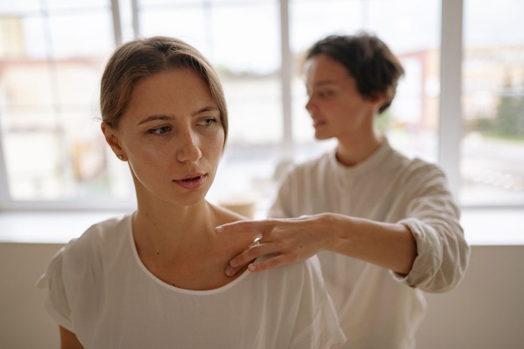 Massage assis en entreprise : praticienne travaillant l'épaule d'une salariée
