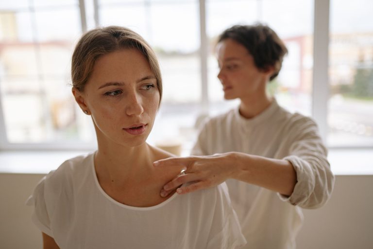 Massage assis en entreprise : praticienne travaillant l'épaule d'une salariée