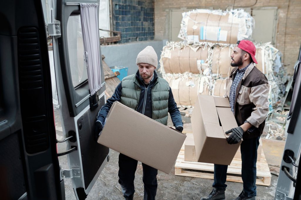 Maladie professionnelle : deux manutentionnaires chargent des cartons dans une camionnette