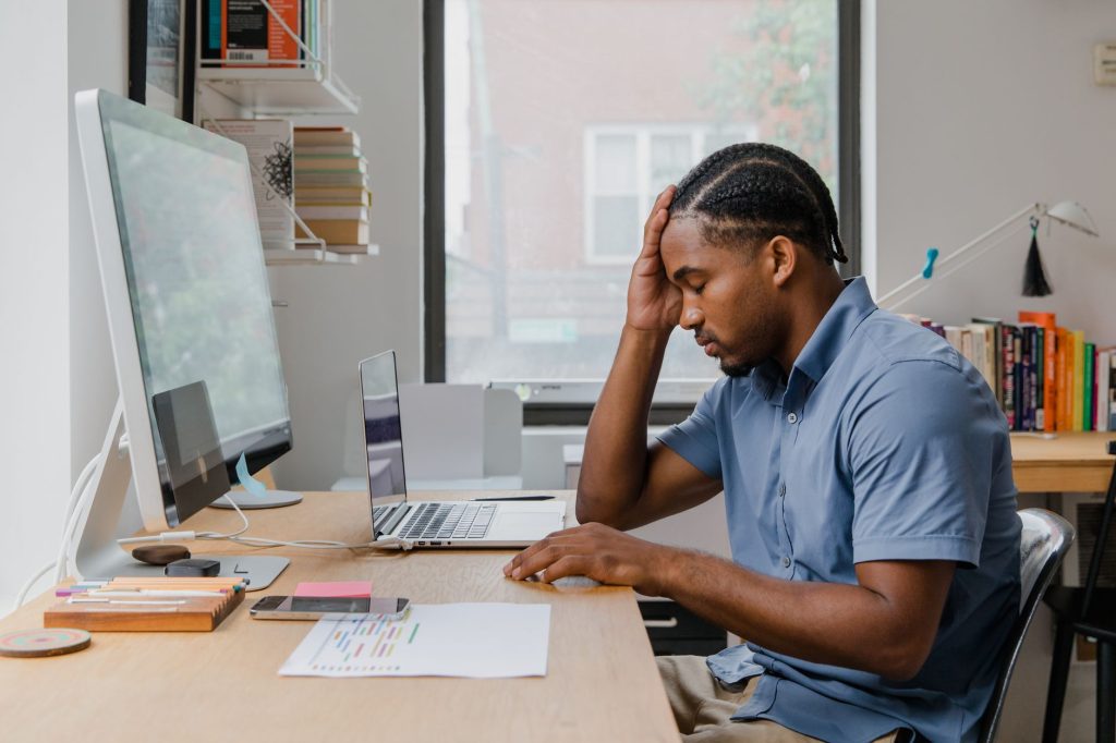 Stress chronique : un salarié épuisé devant son écran, la main sur le front