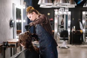 DUERP coiffure : coiffeuse au travail avec une cliente en salon